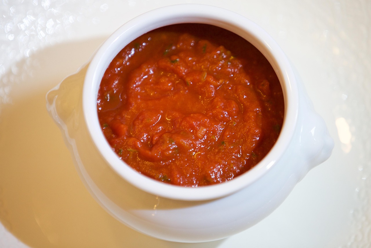 Sugo di pomodoro fresco in una pentola con basilico e ingredienti pronti per la cottura.
